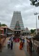 Crowd of devotees visiting Annamalai temple, showcasing intricate architecture and vibrant culture on a cloudy day.