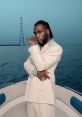 Burna Boy posing confidently on a boat, dressed in a stylish suit against a serene ocean backdrop.