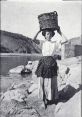 Woman carrying a basket on her head by the river, representing traditional Lavanderas washing practices.