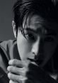 Yunho's intense gaze and striking features highlighted in a dramatic black and white portrait, showcasing his captivating expression.