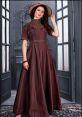 Elegant long brown dress with detailed embroidery, styled with a chic hat, perfect for formal occasions and fashion events.