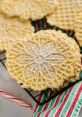 Golden pizzelles dusted with powdered sugar on a festive striped cloth, perfect for holiday celebrations.