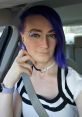 Confident individual with purple hair and glasses, posing in a car, showcasing a chic style and playful vibe.