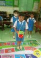 Children engaging in fun educational activity with oversized dice on a colorful game mat in a classroom setting.