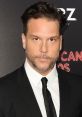 A poised Dane Cook in a black suit, showcasing his signature style at a glamorous red carpet event.