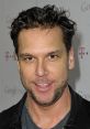 Dane Cook smiling at a public event, showcasing his signature casual style and charismatic presence.