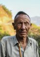 Elderly Paysan with a weathered face and cane, showcasing rural life and rich traditions in a natural landscape.