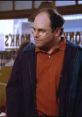 George Costanza in casual attire, looking skeptical in a diner setting, embodying his classic neurotic personality.