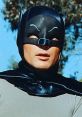 Adam West as Batman, showcasing the iconic costume, with a serious expression in a vintage superhero setting.