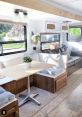 Cozy RV interior featuring a modern dining table, plush seating, and decorative accents for a comfortable travel experience.