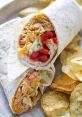 Savory chicken wrap with lettuce, tomatoes, and cheese, served with crispy potato chips on a metal tray.