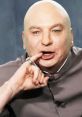 Dr. Evil character, bald with a mischievous expression, gestures playfully while dressed in a gray suit.