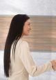 Woman smiling and extending a hand, conveying a warm greeting in a professional setting with a modern background.