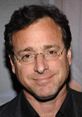 Bob Saget smiling in casual attire, known for his comedy and iconic prank calls. A memorable figure in entertainment history.