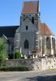 Charming old church with unique architecture and lush greenery, blending history and beauty in a sunny setting.