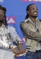 Offset and Quavo showcase their flashy style with jewelry at the MTV VMAs, highlighting their iconic rap presence.