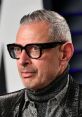 Jeff Goldblum showcasing his iconic style with glasses and a stylish metallic outfit at a glamorous event.