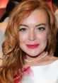 Lindsay Lohan showcasing her signature look with wavy red hair and elegant makeup at a glamorous event, radiating confidence.