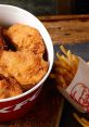 Crispy KFC fried chicken in a bucket, served with golden French fries on a rustic wooden table. Delicious fast food meal.