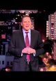 Norm Macdonald performs stand-up comedy in front of a city skyline, showcasing his signature humor and style.