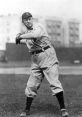 Cy Young preparing to pitch on a baseball field, showcasing classic early 20th-century baseball attire.