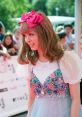 Charming figure in pastel attire with a pink bow, exuding a playful vibe at a vibrant outdoor event.