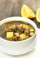 Delicious Hamod soup with greens, lentils, and potatoes, served with lemon slices for a refreshing twist.