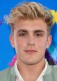 Jake Paul at a promotional event, showcasing his signature style and confident expression against a colorful backdrop.