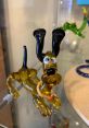 Whimsical yellow glass sculpture of a playful dog with black ears and a colorful collar, showcasing unique craftsmanship.