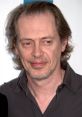 Close-up of Steve Buscemi at an event, showcasing his distinct features and signature hairstyle. Prank call humor personality.