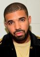 Drake poses with a stylish look, showcasing his trendy haircut and beard against a simple background.