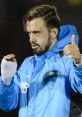 Trevor Phillips giving a thumbs-up, wearing a blue training jacket, showcasing confidence and determination on the field.