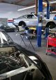 Classic cars being serviced in a modern auto mechanic shop, showcasing tools, lifts, and detailed engine work.