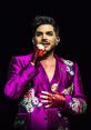 Adam Lambert performing on stage in a vibrant purple suit, showcasing bold fashion and captivating stage presence.