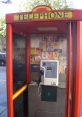 Red telephone booth with ads, showcasing a payphone ideal for prank calls in urban settings.