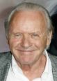 Smiling Anthony Hopkins with light hair, wearing a blazer, exuding charm at a film event. Recognized screen legend.