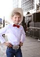 Smiling young boy in cowboy hat and bow tie, embodying the spirit of yodeling and country music culture.