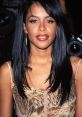 Aaliyah shown with long black hair, wearing a floral dress, capturing her timeless beauty at a 1990s event.