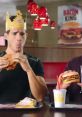 Two men enjoying fast food in a restaurant, featuring a crown and colorful decor, showcasing a fun dining experience.