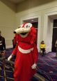 Red character costume referencing "De Way," featuring large expressive eyes and playful design in a convention setting.