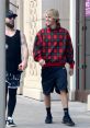 Justin Bieber in a casual plaid hoodie, walking and smiling with a friend on a sunny day. Stylish urban outfit.