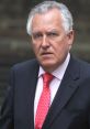 Peter Blackmail in a formal suit, looking serious with a red tie, exemplifying authority and professionalism.