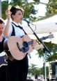 Singer performing live with an acoustic guitar at an outdoor concert, showcasing talent and musical passion.