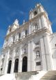 Baroque architecture featuring intricate sculptures and a grand façade against a clear blue sky. Elegant design details.