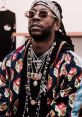 2Chainz showcasing his iconic style with layered chains and vibrant jacket, embodying hip-hop fashion trends.