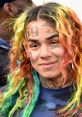 6ix9ine showcases his signature multicolored hair and tattoos, exuding his bold personality and unique style.