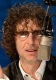 Howard Stern in studio with microphone, engaging in lively conversation, known for his iconic prank calls.