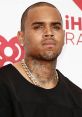 Chris Brown showcasing his unique style at an event, featuring tattoos and a bold fashion statement with a gold chain.