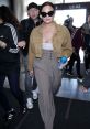 Demi Lovato stylishly arrives at the airport, showcasing her trendy look amidst a crowd. Prank Call: Tom Cruise vibes.