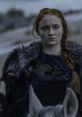 Sansa Stark in Game of Thrones, wearing a fur cloak, with intricate direwolf embroidery, exudes strength and resolve.